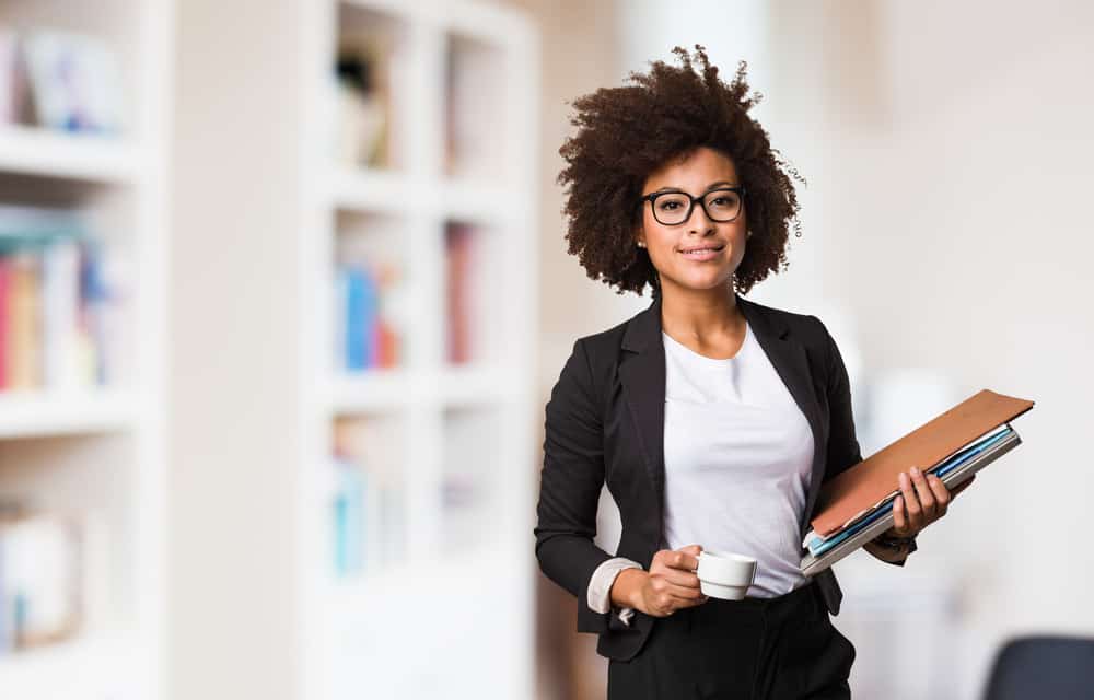 Woman holding documents and coffee.